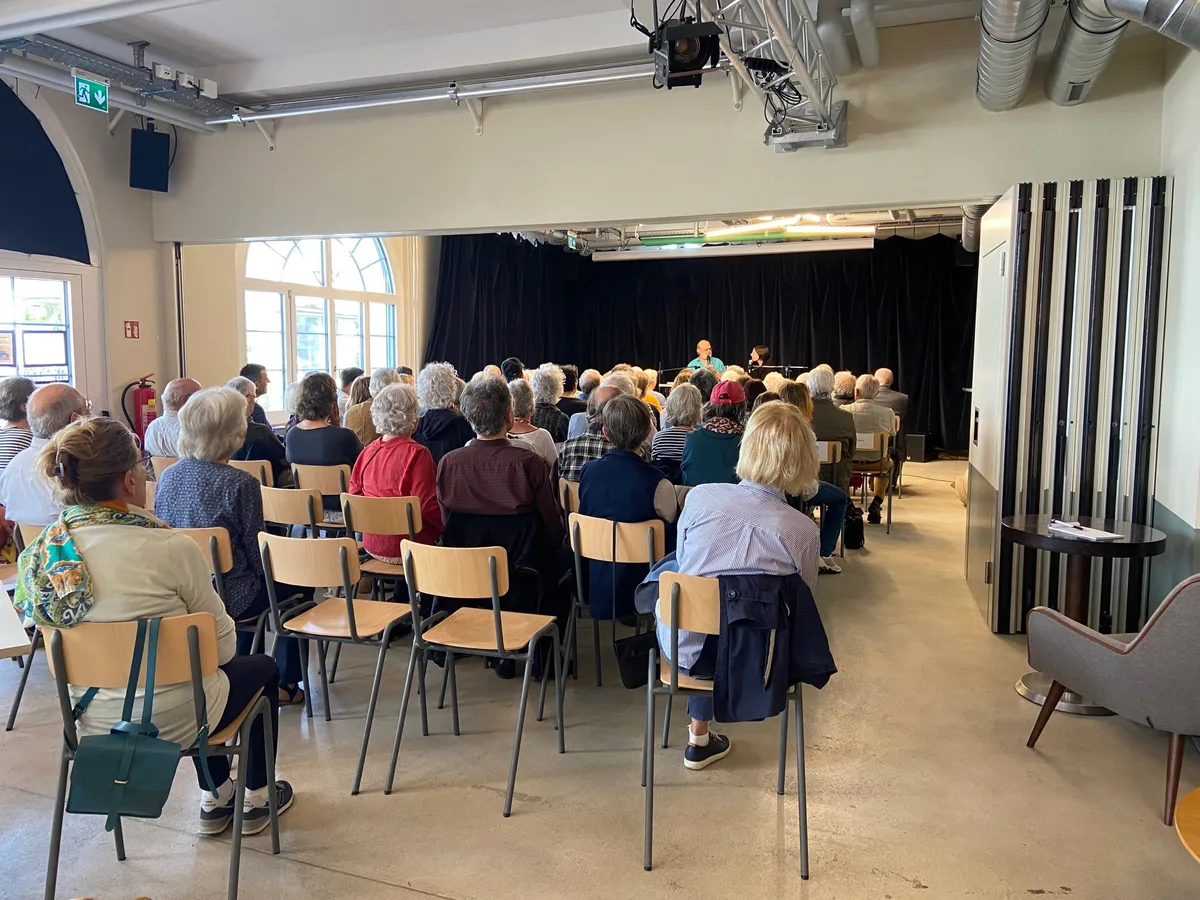 Menschen sitzen auf Stühlen.